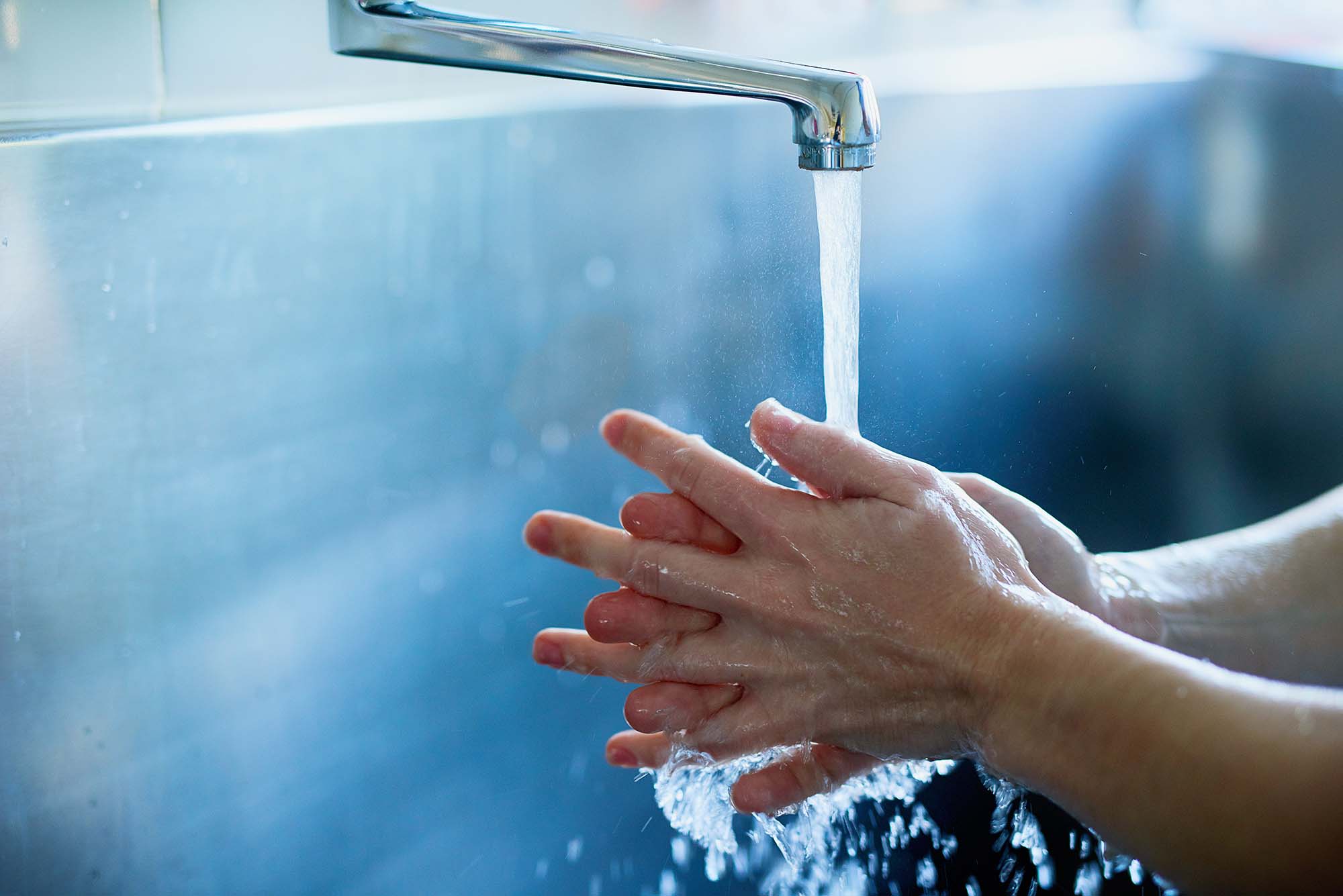 Tvätta händerna under strålande vatten